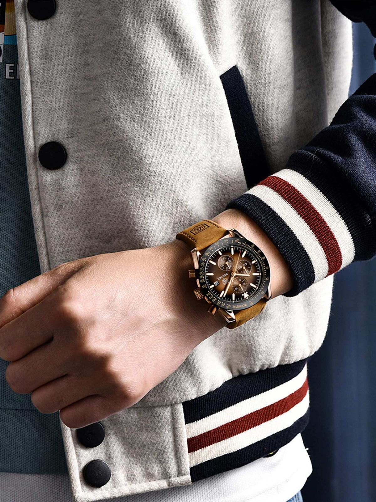 business casual analog watch for men with brown leather strap worn on wrist with varsity jacket