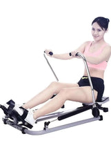Rowing machine with foot straps and padded seat; person using resistance handle