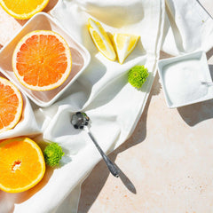 Bowl of BetterBody Foods monk fruit blend sweetener with citrus halves and spoon on white cloth