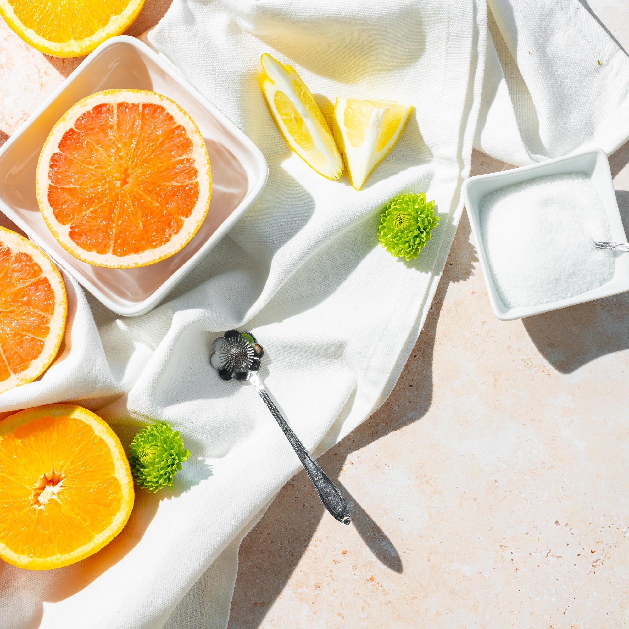 Bowl of BetterBody Foods monk fruit blend sweetener with citrus halves and spoon on white cloth