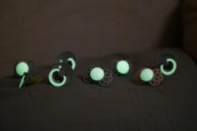 Glow-in-the-dark pacifiers with soft green light on the shields and round nipples