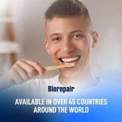 Smiling young man brushing teeth with wooden toothbrush and Biorepair logo promoting Biorepair toothpaste UAE worldwide