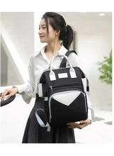 Baby travel backpack worn on shoulder with white contrast front panel and top handle