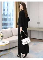 Elegant black brown two-piece outfit for ladies styled with black heels and white handbag indoors