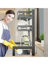Black dish drying rack with sink basin and utensil hooks in a kitchen