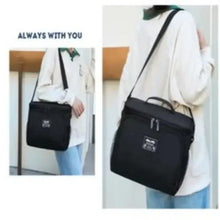 Black insulated lunch box bag with shoulder strap and zip closure, worn crossbody.