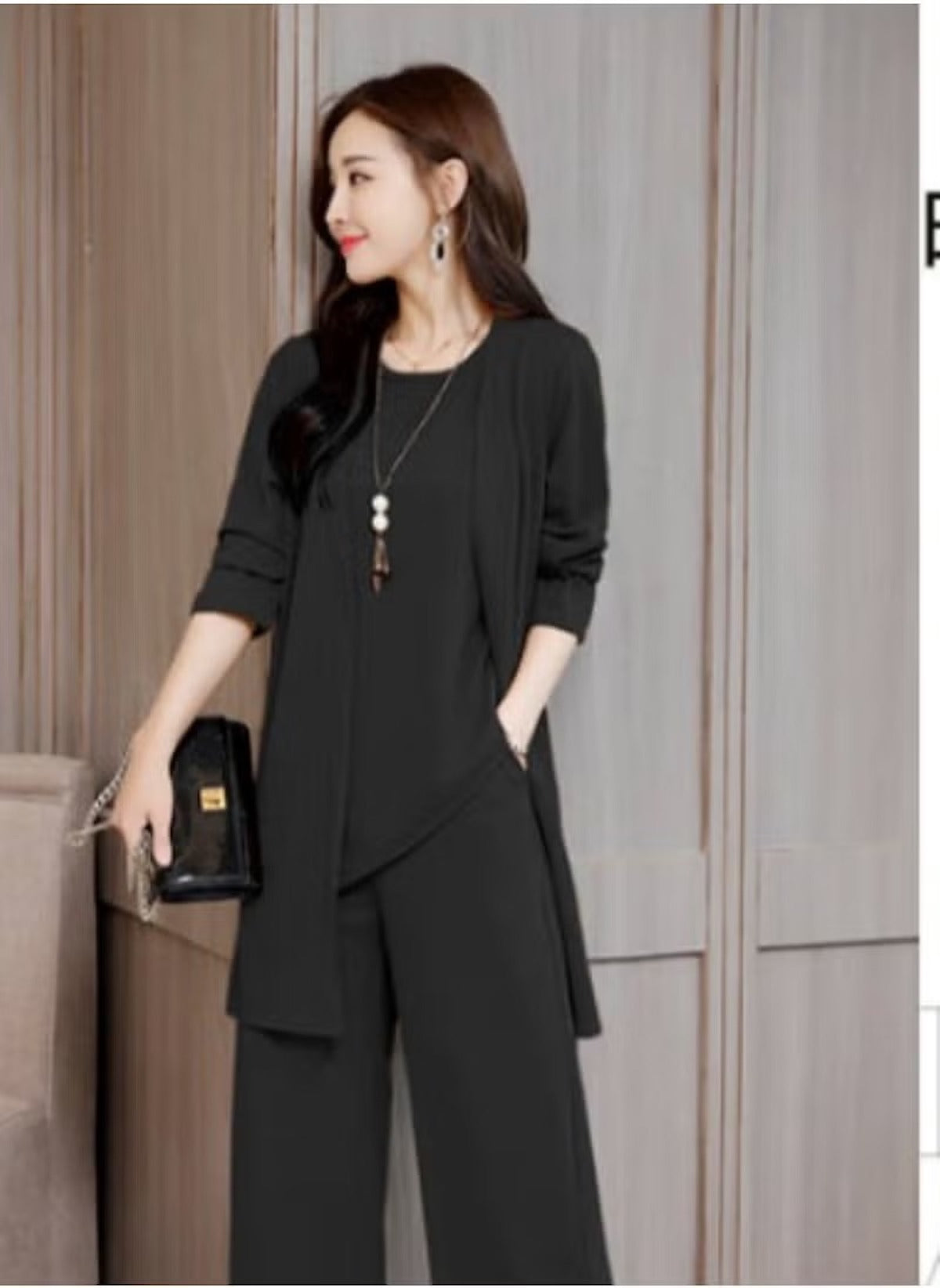 Woman wearing black three-piece slim suit for women with long jacket and wide-leg pants
