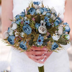 Huitich blue artificial flower bouquet with green leaves and pink accents held by person in white dress