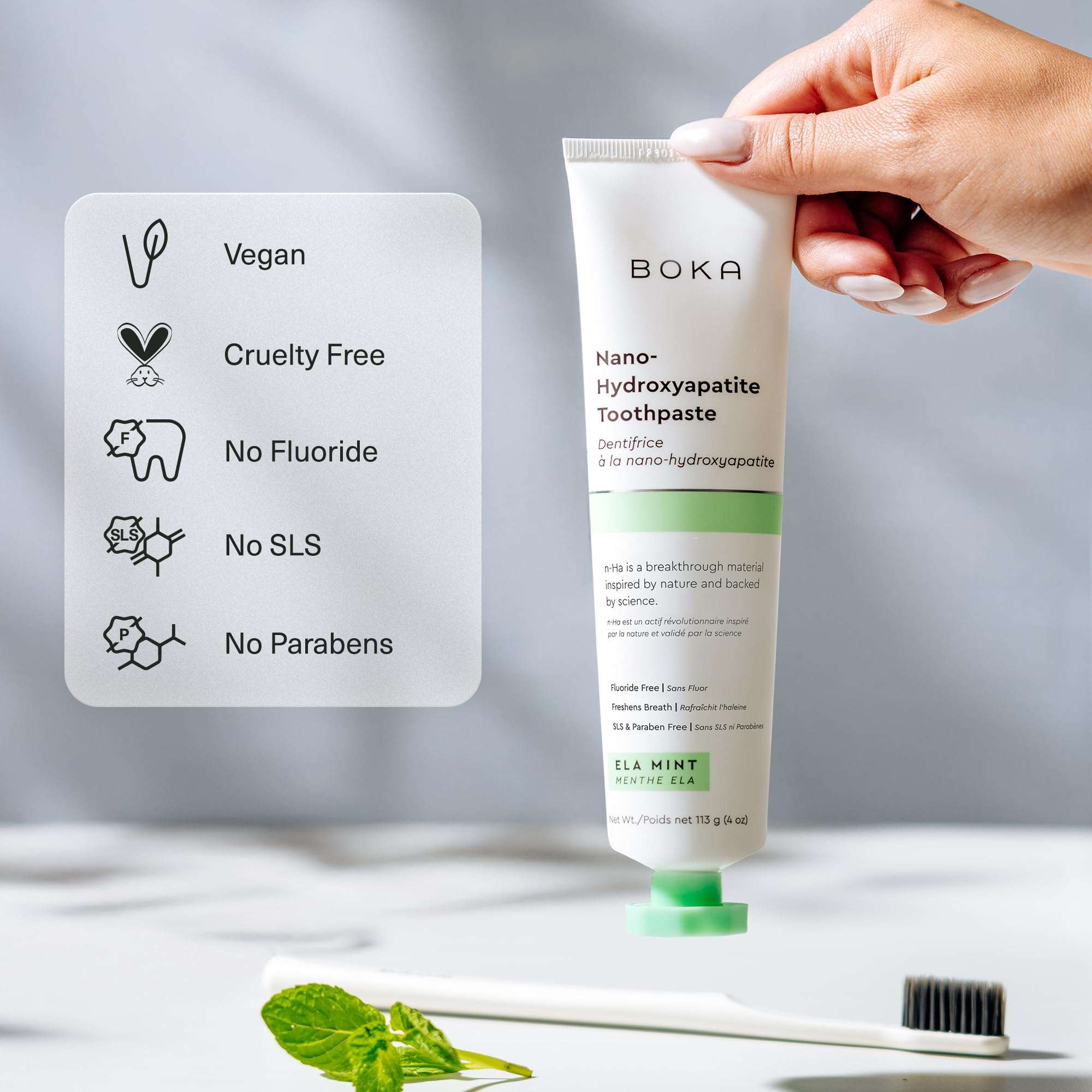 Boka nano hydroxyapatite toothpaste tube held by hand with mint and toothbrush fluoride free toothpaste for sensitive teeth