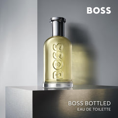 Boss Bottled Eau De Toilette for men in clear glass bottle with silver cap on grey background