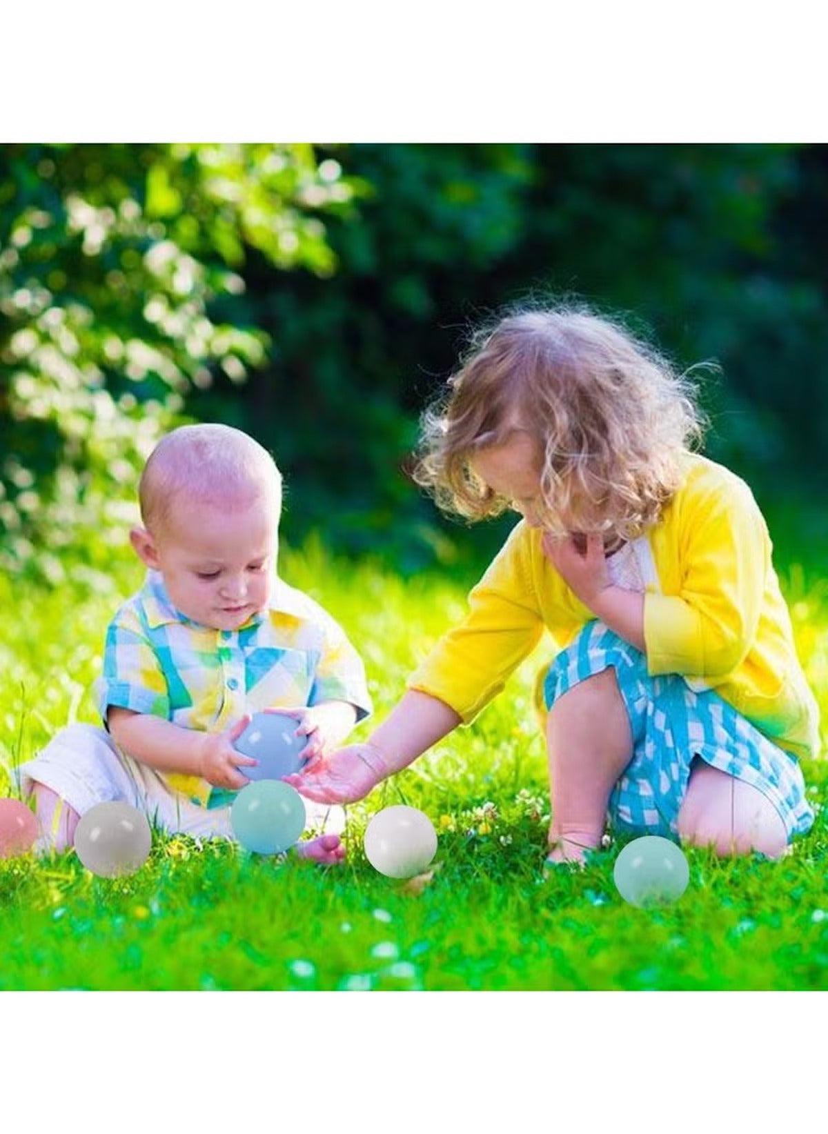 Two toddlers playing outdoors with Huitich BPA-free play ball pit balls on green grass