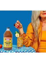 Bragg apple cider vinegar bottle on table beside a mixing glass