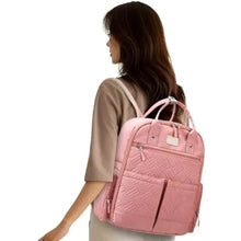Pink quilted diaper backpack worn on shoulder with side pocket