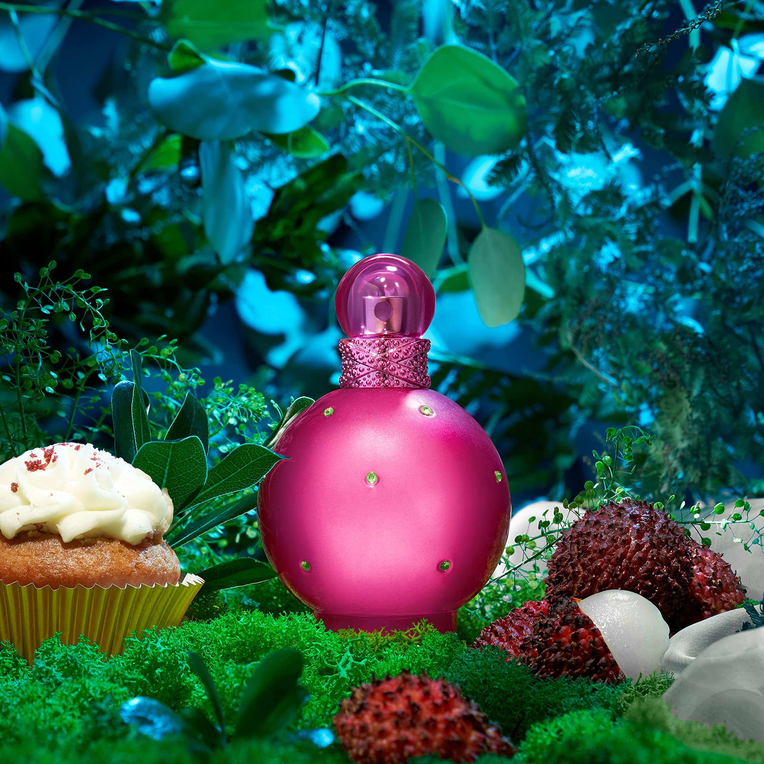 Best floral fruity perfume for women in a pink round bottle surrounded by green foliage and fruits