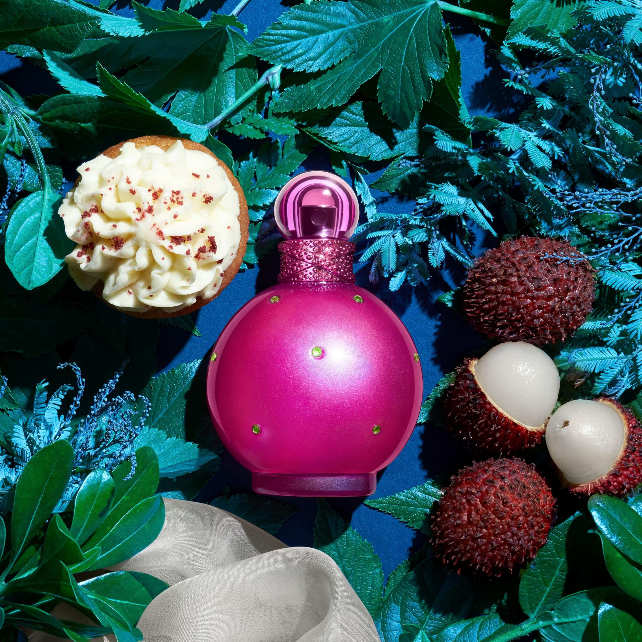 Pink perfume bottle surrounded by tropical fruits and green leaves for best floral fruity perfume for women