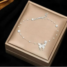Silver pearl beaded necklace with butterfly charm, displayed in a jewelry box.