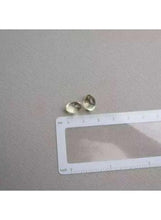 Vitamin D3 softgels, two oval capsules, measured beside a ruler with inch markings