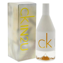 Perfume bottle with CK gold logo beside upright IN2U her box