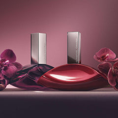 Two elegant Calvin Klein Euphoria perfume for women bottles with pink orchids on a purple background