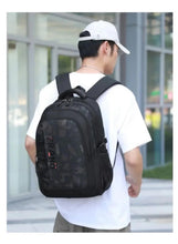 Camouflage school backpack worn on back, dark gray camo front and top handle