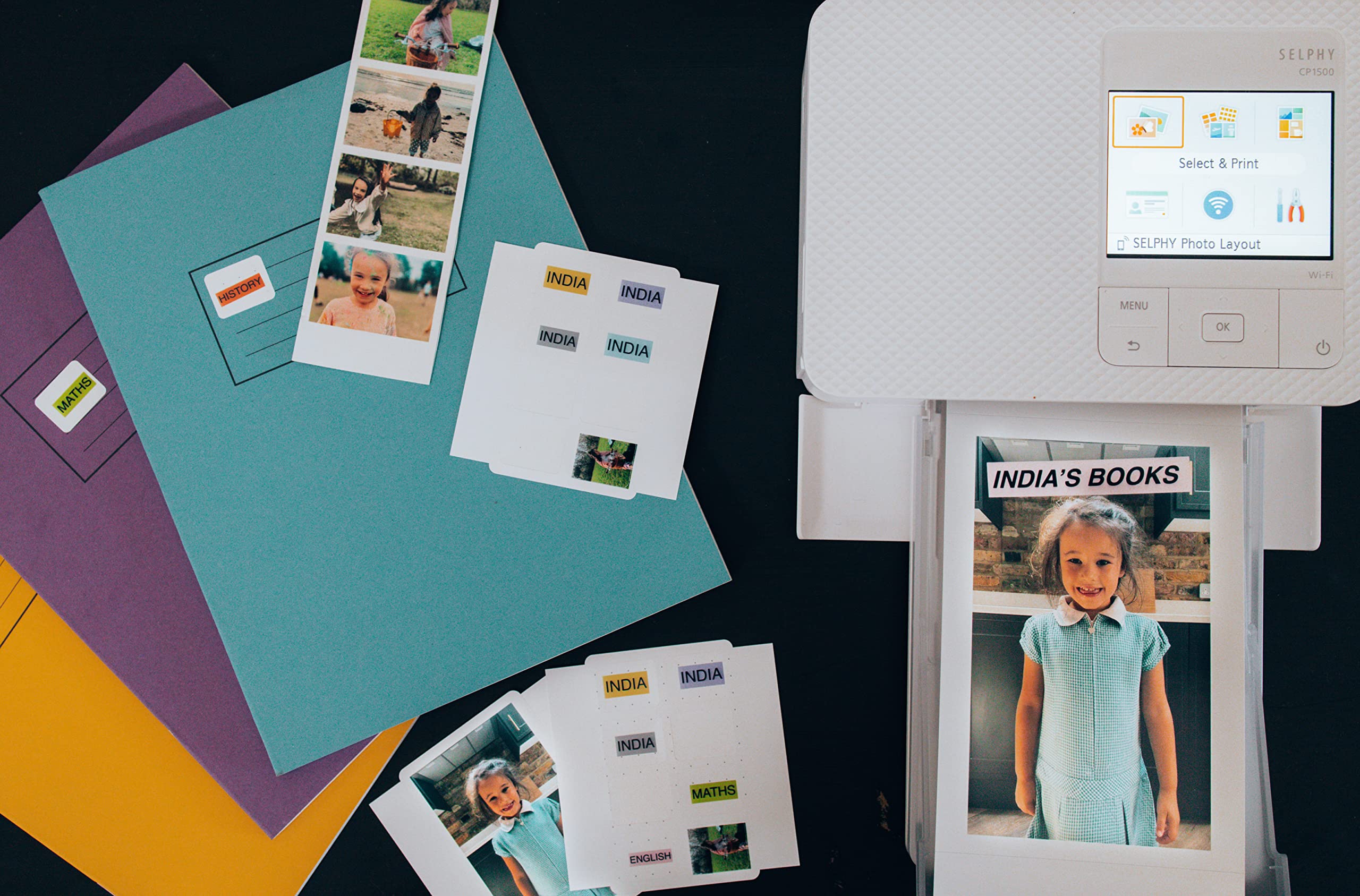 Canon RP108 ink and paper set with photo printer printing a child's portrait and colorful photo papers