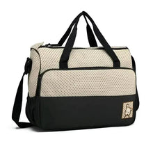 Diaper bag with cream dotted fabric, black base, long shoulder strap and front pocket