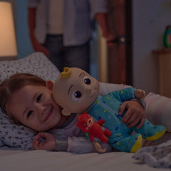 Child lying in bed holding Huitich Cocomelon stuffed doll gift in blue pajamas with yellow feet
