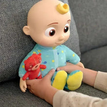 Stuffed baby doll in light blue patterned outfit with yellow feet, cuddling red mini plush