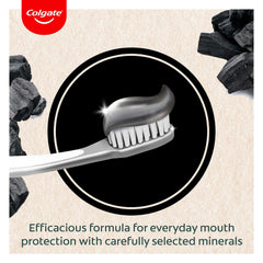 Colgate charcoal toothpaste UAE black charcoal paste on toothbrush with charcoal pieces and Colgate logo