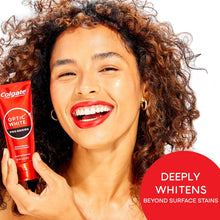 Smiling person holding a red Optic White Pro Series whitening toothpaste tube