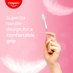 Hand holds pink Colgate sensitive toothbrush pack showing soft bristles and superior handle for comfortable grip