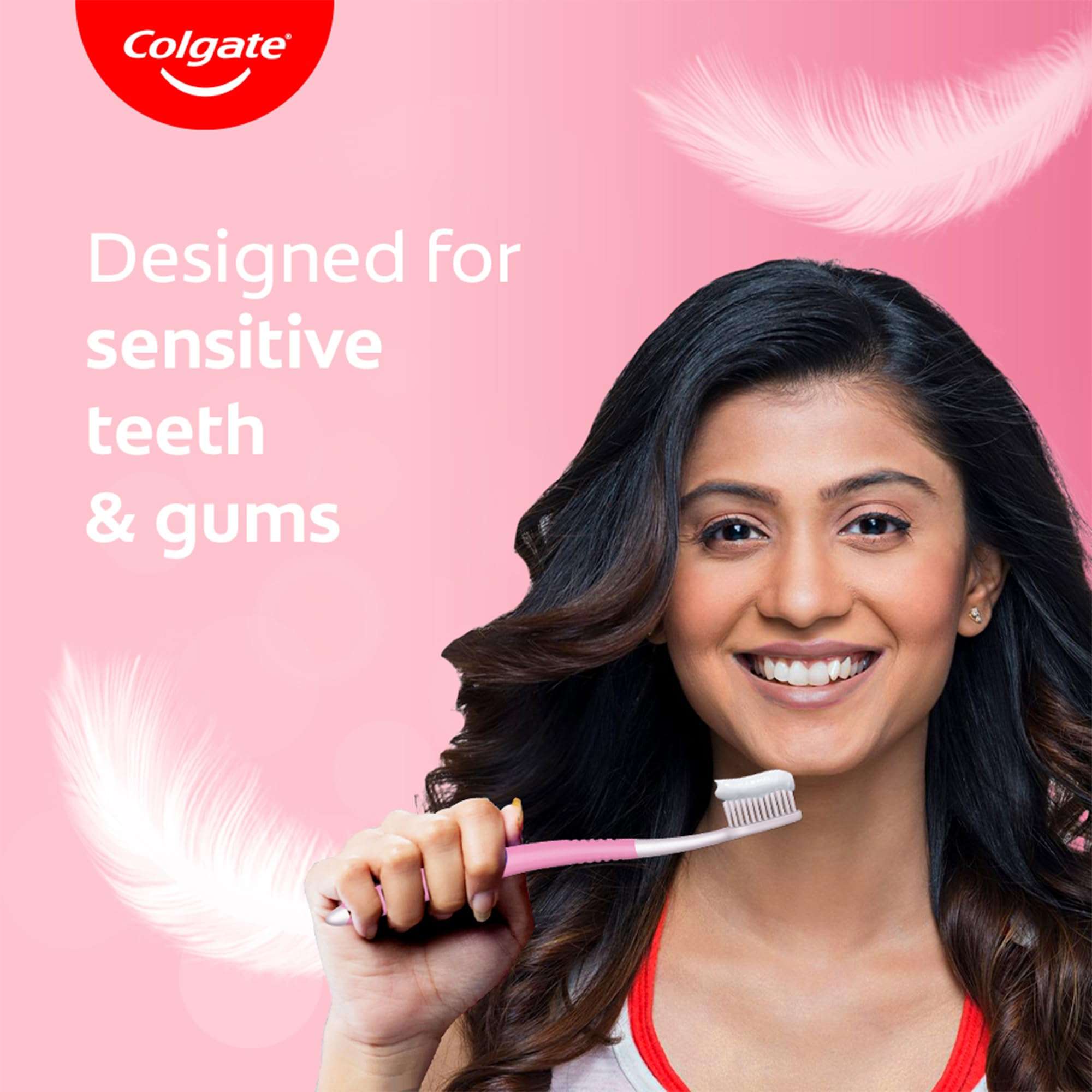Woman smiling holding pink brush on pink background with feather graphics Colgate sensitive toothbrush pack