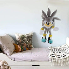 Gray Sonic-style plush standing on a bed near pillows