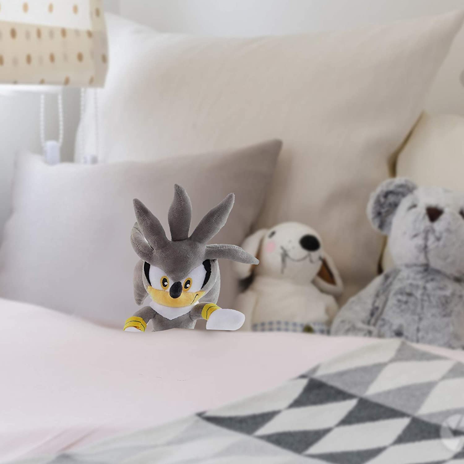 Huitich collectible sonic plush toy in gray and yellow colors placed on a bed with stuffed animals in the background