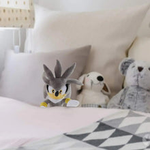 Gray Sonic-style plush doll lying on bed, yellow muzzle and blue shoe tips