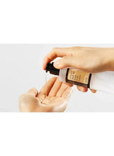 Essence bottle dispensing a drop onto open fingers for skincare use