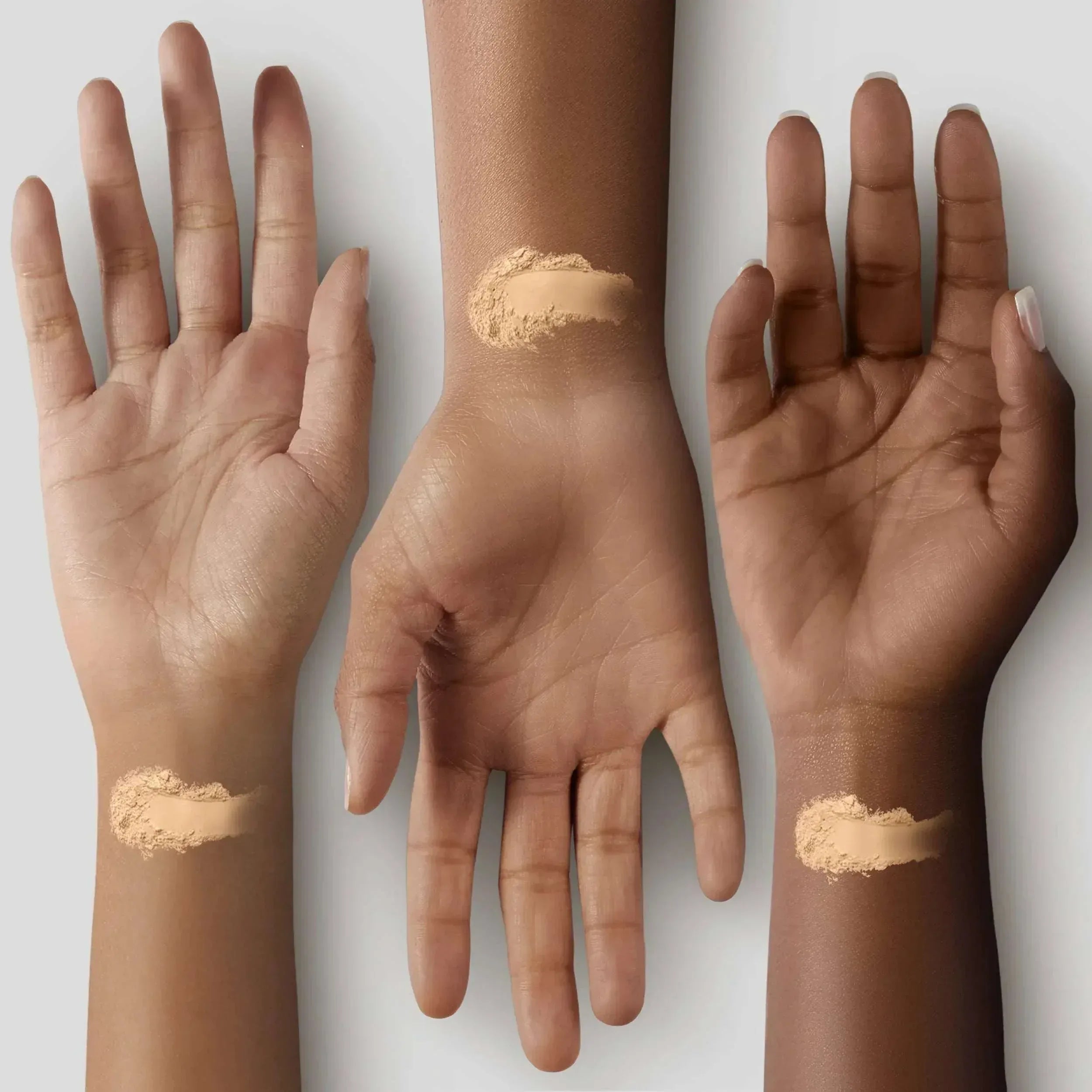 Pressed face powder swatches on hands and wrists, tan beige powder lines