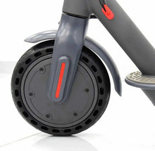 Front wheel of dark grey electric scooter with red reflector stripe and tire tread