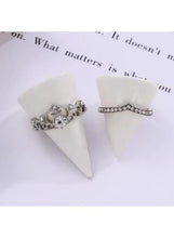 Two silver tone rings: crown ring with central round stone, and slim band with clear stones