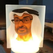 Portrait table lamp with white rectangular shade, bearded face print, glowing light