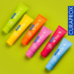 Six colorful Curaprox Be You gentle whitening toothpaste tubes on lime green background showing vibrant packaging
