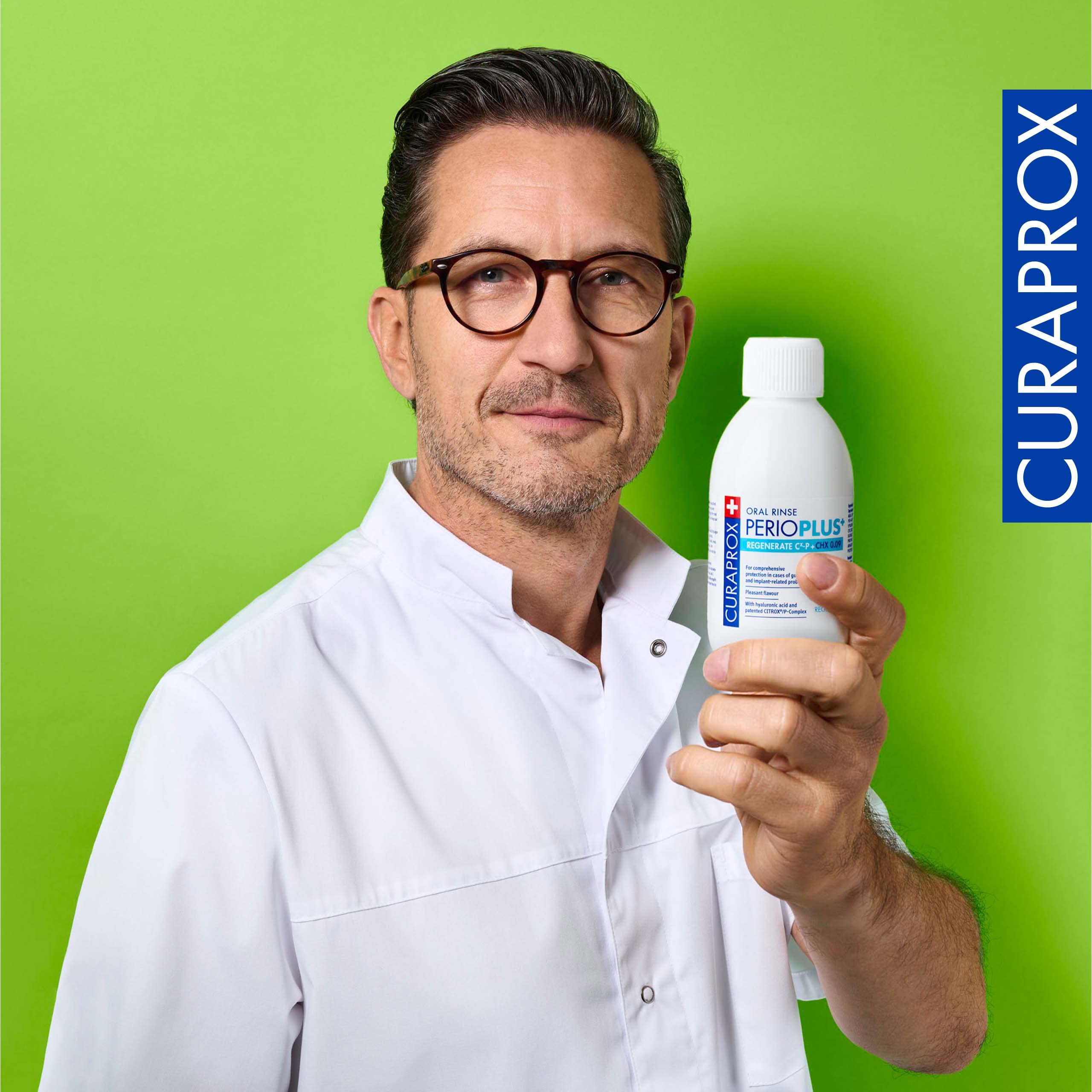 Dentist in white coat holding Curaprox Perio Plus Regenerate mouthwash bottle on green background