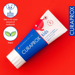 Curaprox kids fluoride toothpaste strawberry flavor tube on red background with vegan and dosing icons