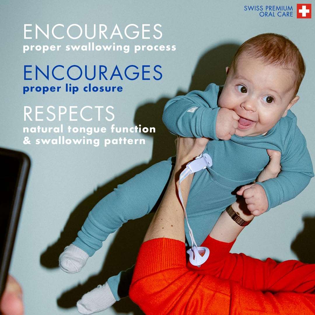 Smiling baby in teal onesie held by caregiver with clip attached to orthodontic baby pacifier UAE promoting proper lip closure