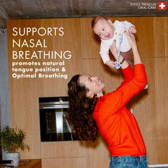 orthodontic baby pacifier UAE in use with smiling mother lifting infant in kitchen supports nasal breathing