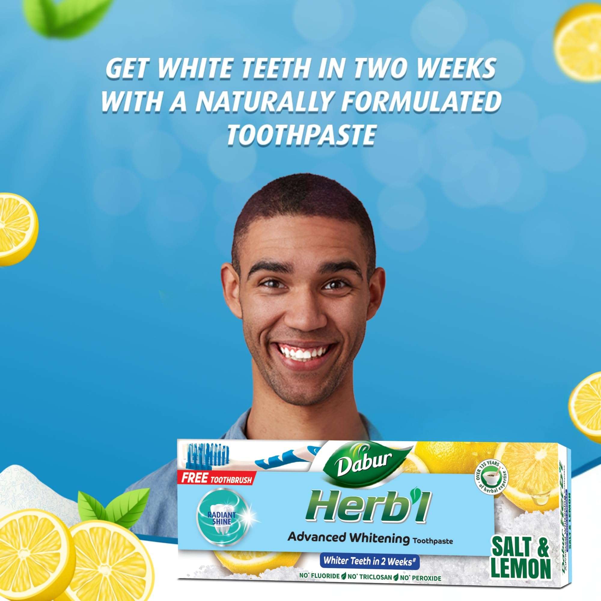 Smiling man with Dabur Herbl whitening toothpaste value pack Salt and Lemon box showing free toothbrush and lemons