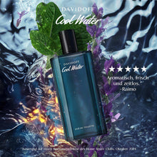 Teal eau de toilette bottle with black cap beside green leaves and purple flowers