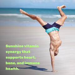 Fit man doing a handstand on a sunny beach wearing swim trunks promoting Vitamin D3 10000 IU with K2 supplement