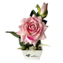 Artificial pink rose in white decorative pot with green leaves
