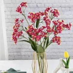 Huitich decorative fake roses for weddings in vibrant pink with green leaves in a clear glass vase